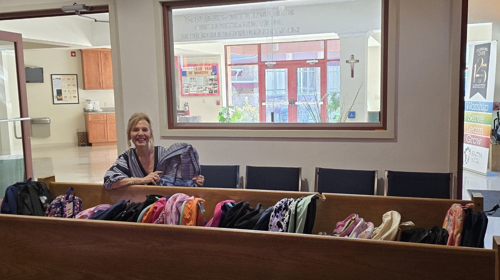 Pastor Jane McCready stands with backpacks ready for delivery to St. John's Roman Catholic Soup Kitchen in Newark.