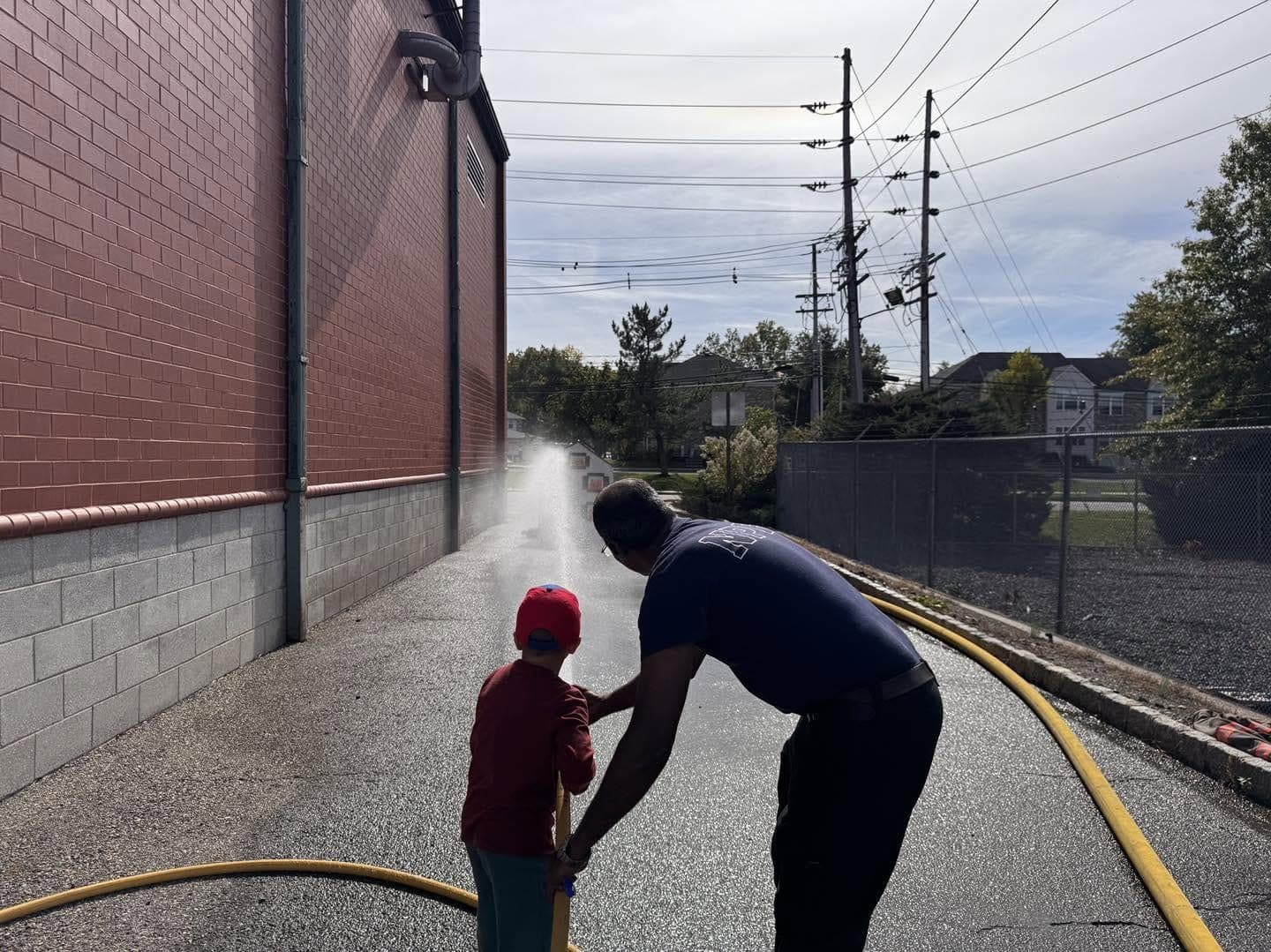 A New Providence firefighter helps a young visitor aim a hose line during the department’s annual open house.